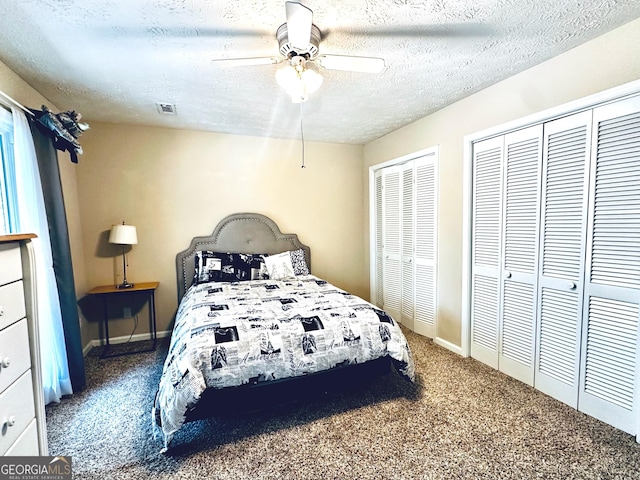 carpeted bedroom with baseboards, a textured ceiling, visible vents, multiple closets, and ceiling fan