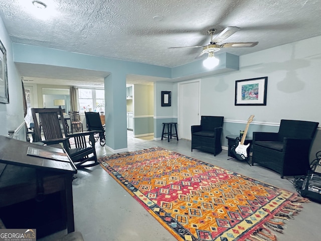 living room featuring concrete floors, ceiling fan, baseboards, and a textured ceiling