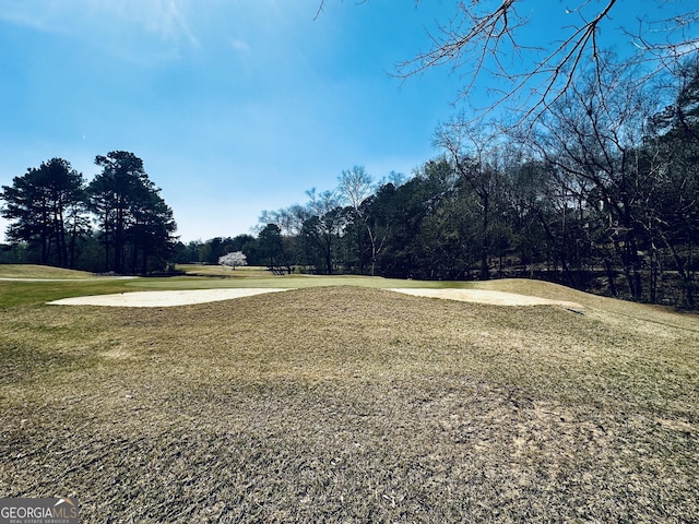 view of property's community with view of golf course and a yard