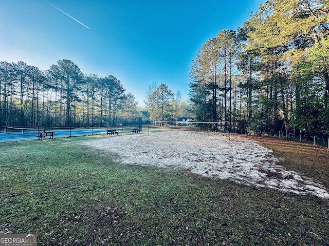 view of property's community with a tennis court, fence, volleyball court, and a lawn