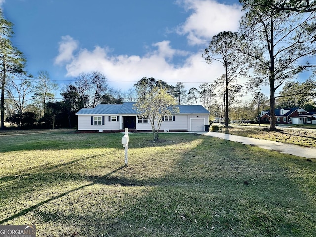 view of front of home with an attached garage, concrete driveway, a front yard, and metal roof