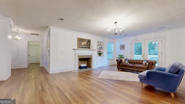 living room with visible vents, a fireplace with flush hearth, a textured ceiling, and an inviting chandelier