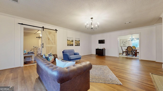 living room featuring a barn door, wood finished floors, visible vents, and a chandelier