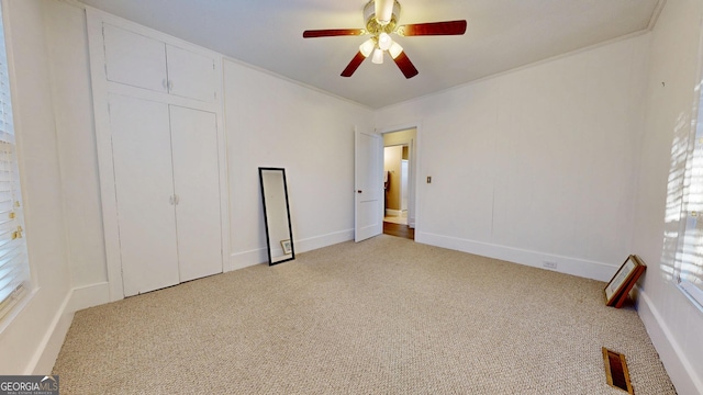 unfurnished bedroom featuring visible vents, a ceiling fan, a closet, carpet floors, and crown molding