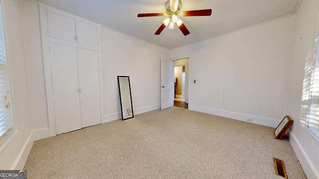 unfurnished bedroom featuring crown molding, a closet, a ceiling fan, visible vents, and carpet flooring