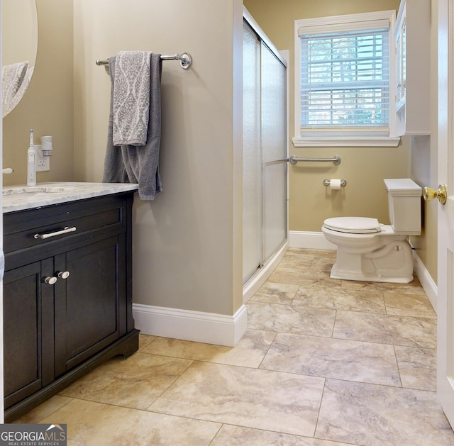 full bath featuring a stall shower, toilet, vanity, and baseboards