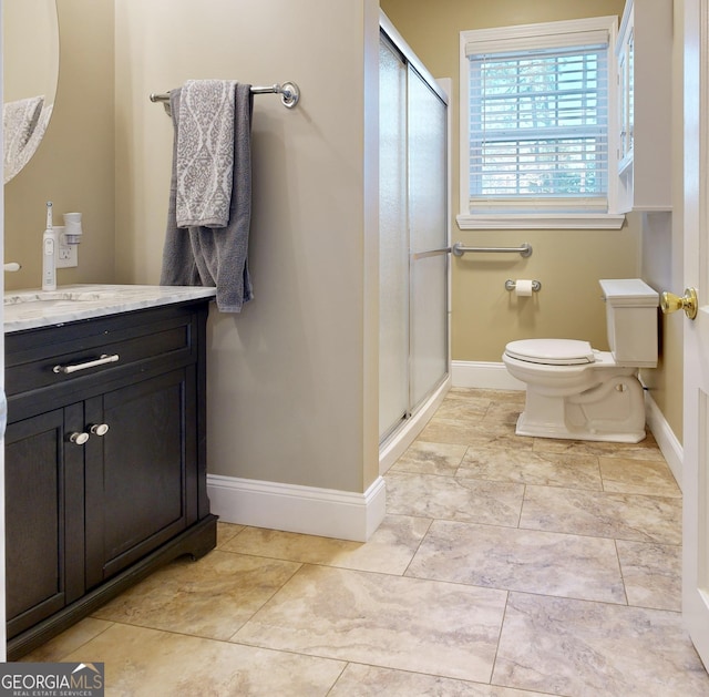 bathroom with a shower stall, vanity, baseboards, and toilet