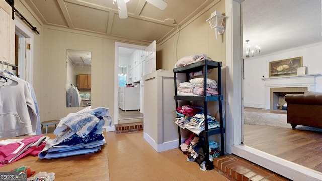 bedroom with a fireplace with flush hearth, washer / dryer, crown molding, and a decorative wall