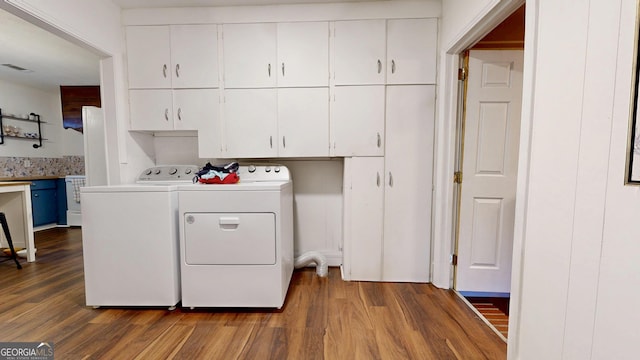 laundry area with washing machine and clothes dryer, visible vents, cabinet space, and dark wood finished floors