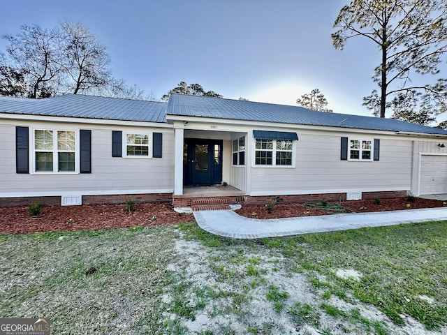 single story home featuring metal roof, a front yard, covered porch, and a garage