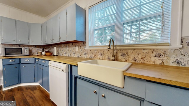 kitchen with stainless steel microwave, ornamental molding, light countertops, white dishwasher, and a sink