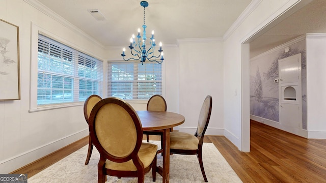dining room with a chandelier, visible vents, crown molding, and wood finished floors