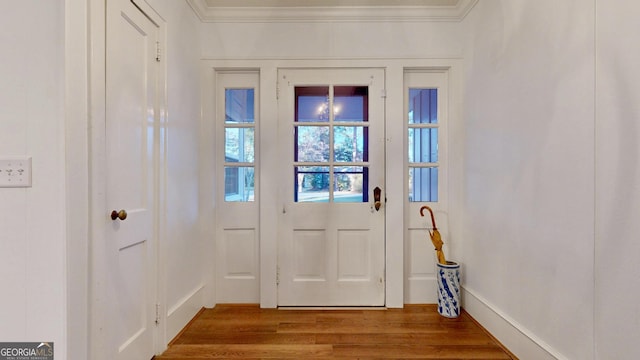 doorway with crown molding, baseboards, and wood finished floors