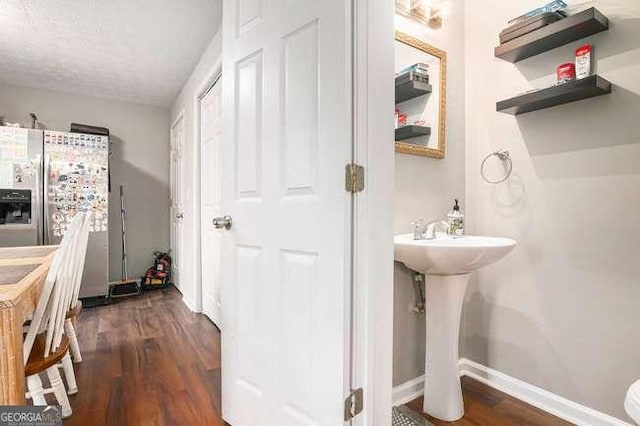 bathroom with a sink, a textured ceiling, baseboards, and wood finished floors