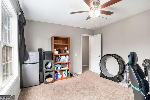 interior space with baseboards, carpet, attic access, and ceiling fan