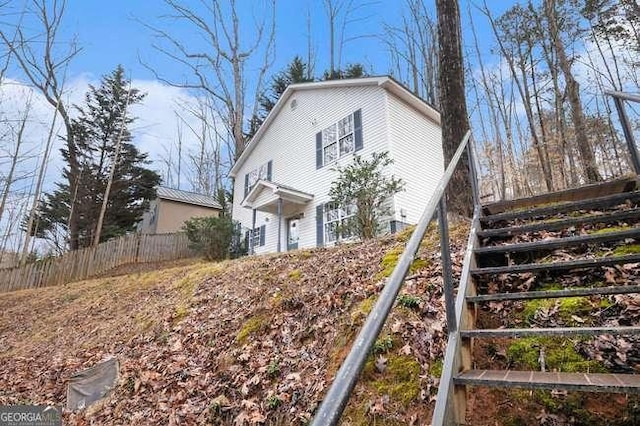 view of property exterior featuring stairway and fence