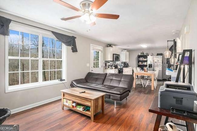 living room with baseboards, dark wood-style floors, and a ceiling fan