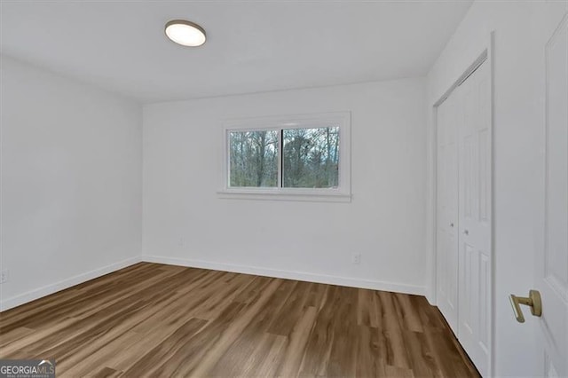 unfurnished bedroom with a closet, baseboards, and wood finished floors