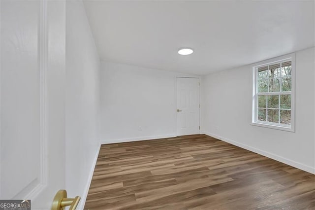 spare room with baseboards and wood finished floors