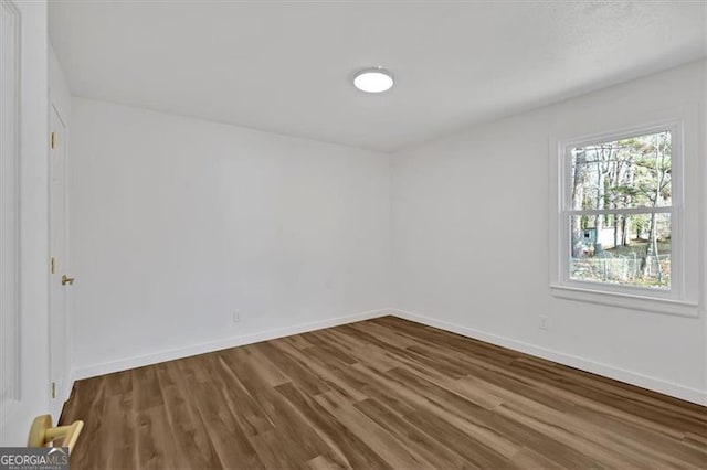 spare room with baseboards and wood finished floors