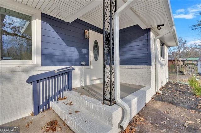 doorway to property featuring brick siding and a porch