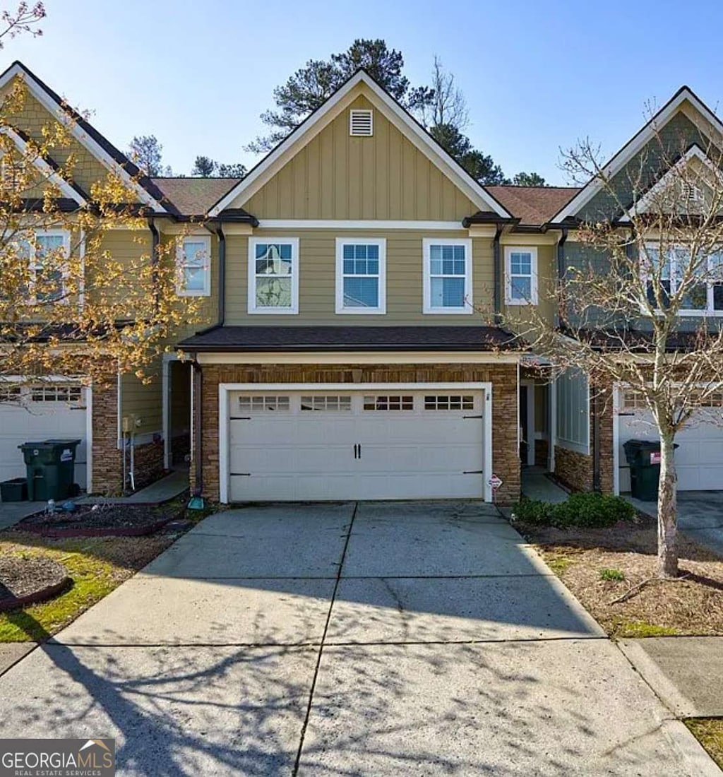 view of front of house with a garage, stone siding, board and batten siding, and concrete driveway