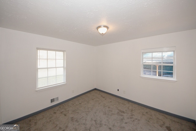 carpeted empty room featuring visible vents, baseboards, and a textured ceiling