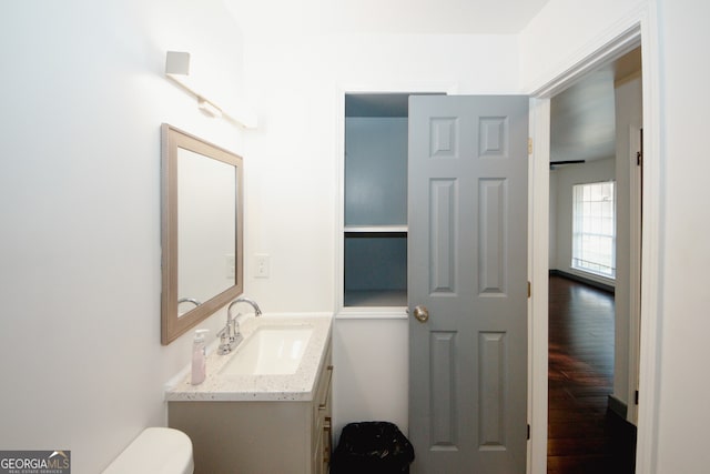 half bath with vanity, toilet, and wood finished floors