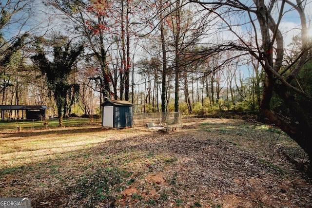 view of yard featuring a storage unit, an outdoor structure, and fence