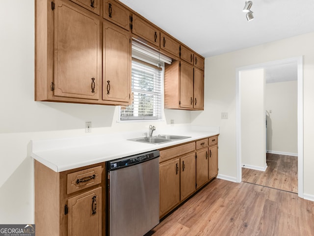 kitchen with light wood finished floors, baseboards, dishwasher, light countertops, and a sink