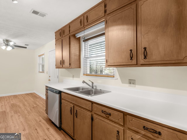 kitchen featuring visible vents, light wood finished floors, a sink, stainless steel dishwasher, and light countertops