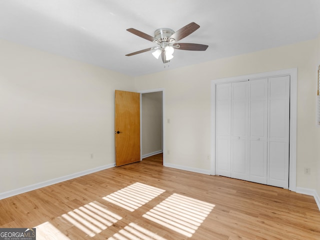 unfurnished bedroom featuring a closet, a ceiling fan, baseboards, and light wood finished floors