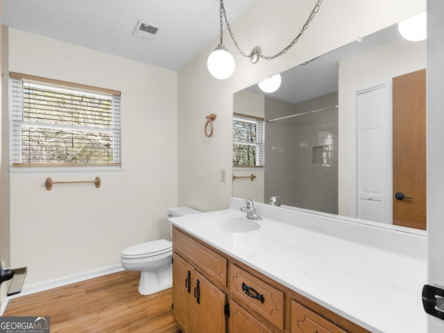 full bath with visible vents, walk in shower, toilet, wood finished floors, and vanity