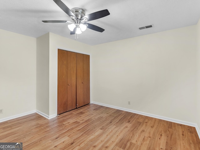 unfurnished bedroom with visible vents, baseboards, light wood-style flooring, a closet, and a ceiling fan