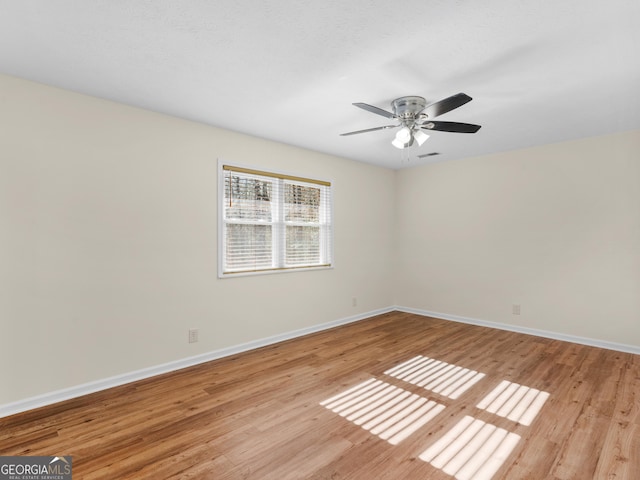 spare room with ceiling fan, visible vents, light wood-type flooring, and baseboards