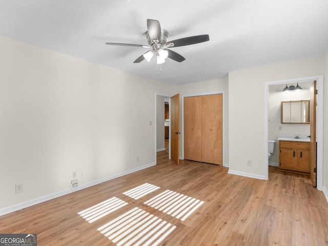 unfurnished bedroom with light wood-style flooring, a sink, ensuite bath, a closet, and baseboards