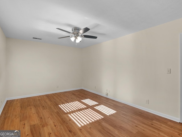 empty room featuring wood finished floors, visible vents, and baseboards