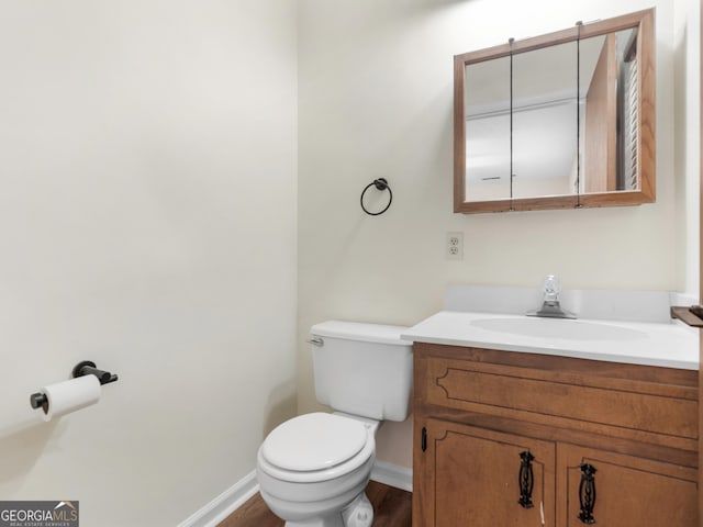 bathroom with toilet, vanity, baseboards, and wood finished floors