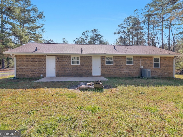 rear view of property featuring a yard, a patio, brick siding, and central air condition unit