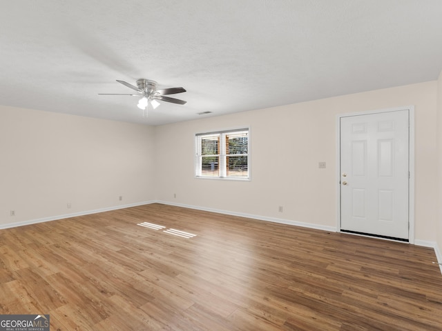 unfurnished room with baseboards, light wood-style flooring, and a ceiling fan