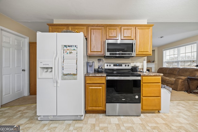 kitchen with open floor plan, appliances with stainless steel finishes, and brown cabinets