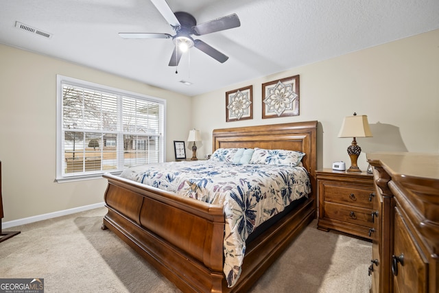 bedroom with a ceiling fan, visible vents, baseboards, a textured ceiling, and light colored carpet