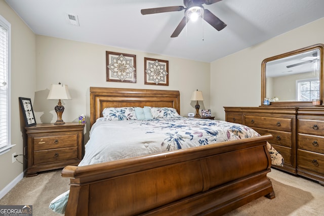 bedroom featuring light carpet, visible vents, a ceiling fan, and baseboards