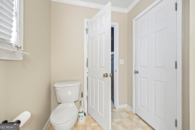 bathroom featuring baseboards, toilet, and crown molding