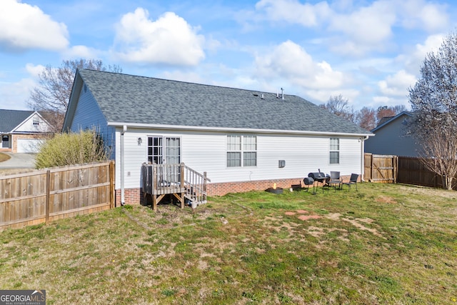 rear view of house featuring a lawn, roof with shingles, and a fenced backyard