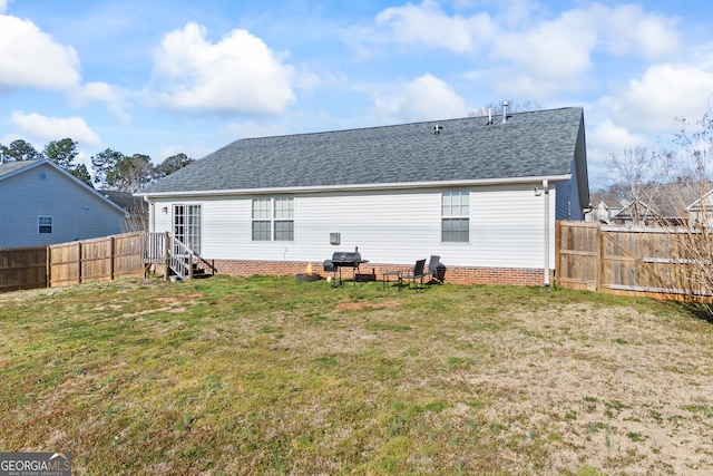 rear view of house featuring a lawn, roof with shingles, and a fenced backyard