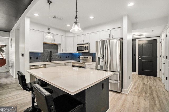 kitchen with a sink, light wood-type flooring, backsplash, and appliances with stainless steel finishes