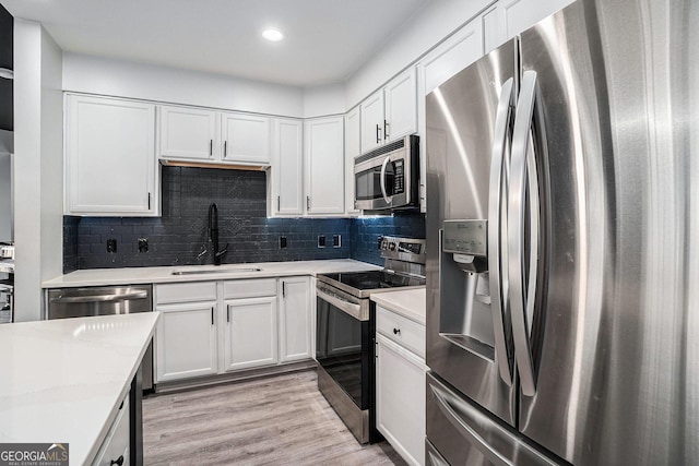 kitchen featuring light countertops, appliances with stainless steel finishes, light wood-style floors, white cabinetry, and a sink