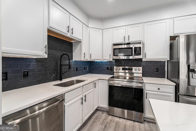 kitchen with a sink, light countertops, white cabinets, and stainless steel appliances