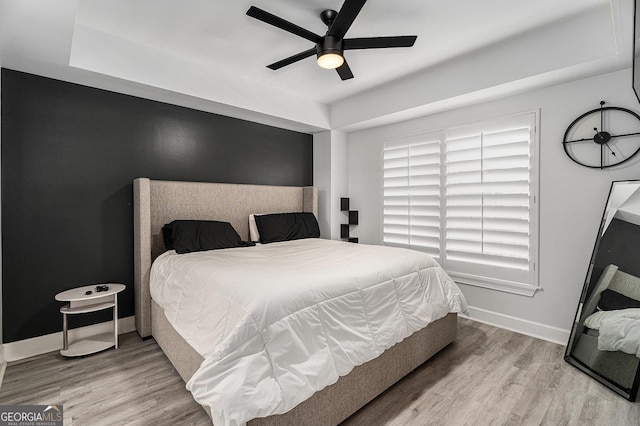 bedroom with a ceiling fan, baseboards, and wood finished floors